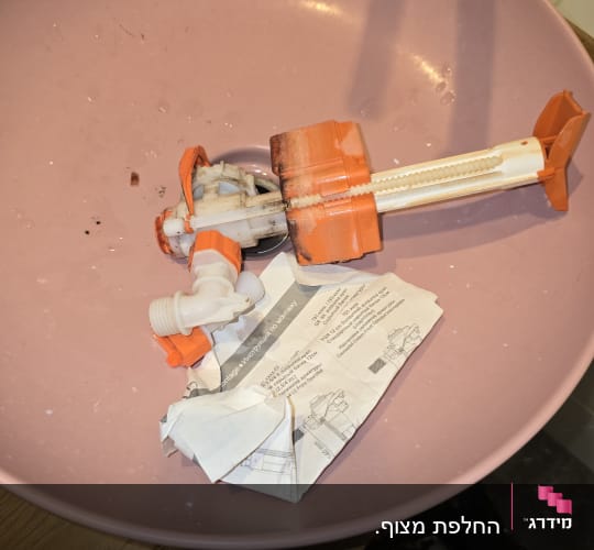 חלקי אינסטלציה בקערה ורודה על שולחן